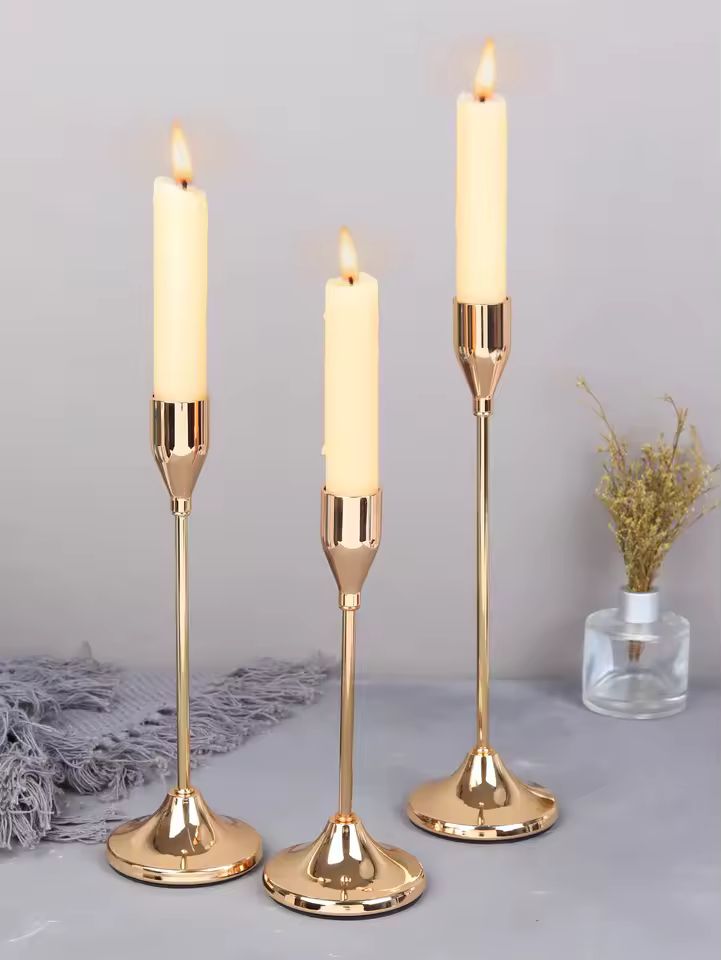 Luxury gold Éclat candle holder set with three lit candles on a minimalist tabletop.